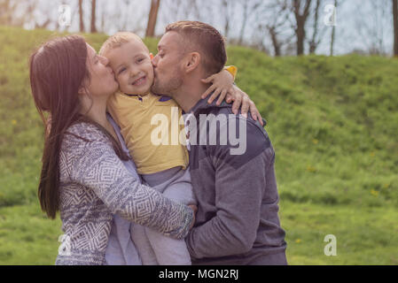 Parents having fun with their child in park. Beautiful family is having fun outside. Mom with dad are playing with their little son on playground. Stock Photo