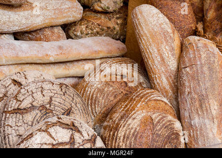 A selection of artisan bakery bred rolls and loaves on display at a bakers stall on borough market in london. Freshly baked artisan bread at bakery. Stock Photo