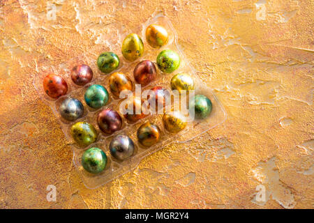 Easter multicolored dyed bright quail eggs.Full pack of eggs corner on orange background. Top view. Copy space Stock Photo