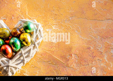 Easter eggs in nest over wooden background. Top View with copy space.easter nest with colored eggs on yellow background.Quail egg in nest, spring Stock Photo