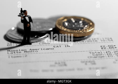 Miniature scale model waiter on a till receipt bill with british coins tip Stock Photo