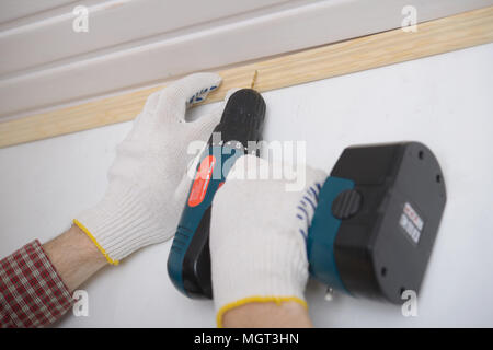 Contractor installing molding to ceiling using cordless power drill Stock Photo