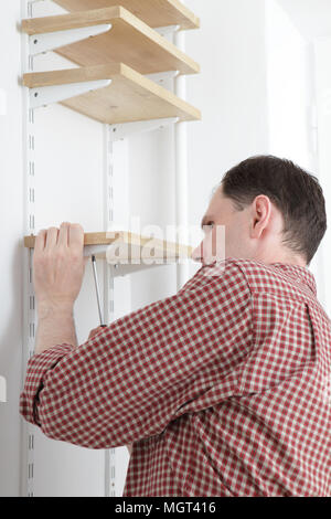 Man installing wooden shelves on brackets