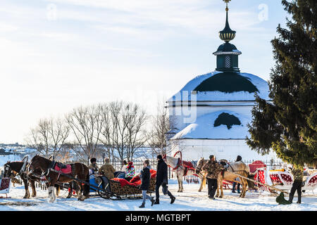 SUZDAL, RUSSIA - MARCH 9, 2018; people on horse sledges near Church of St Paraskeva or Pyatnitskaya Church in Suzdal town in sunny winter day winter Stock Photo