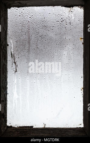 water drops from melting snow on surface of misted window in old rural house in winter Stock Photo