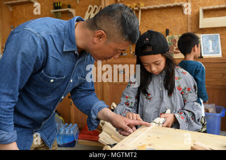 Beijing, China. 29th Apr, 2018. A girl learns about woodworking in Shijingshan Amusement Park during a spring fete in Beijing, capital of China, April 29, 2018. The fete, decorated by various pinwheels, kicked off on Sunday. Credit: Li Jundong/Xinhua/Alamy Live News Stock Photo