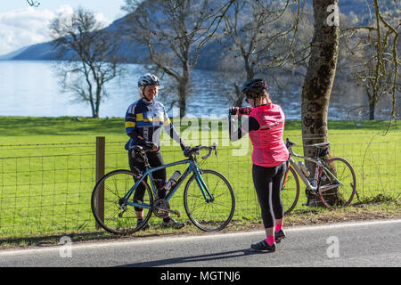 Fort Augustus, Scotland, UK. 29th April, 2018. Cyclists taking part in the Etape Loch Ness closed road cycle sportive following a 360-degree 66-mile / 106-Km route around Loch Ness, Scotland, starting and finishing in Inverness. This event is expected to attract 5,600 cyclists from across Scotland and the UK. Thousands of pounds will be raised by participants for Macmillan Cancer Support, the official event charity. This image shows participants stopping to take photos at the half way point near Fort Augustus. Cliff Green/Alamy Live News Stock Photo