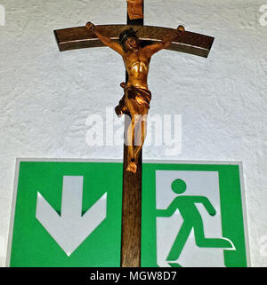 Crucifix over an emergency exit, escape sign in a restaurant in Fulda, Germany Stock Photo