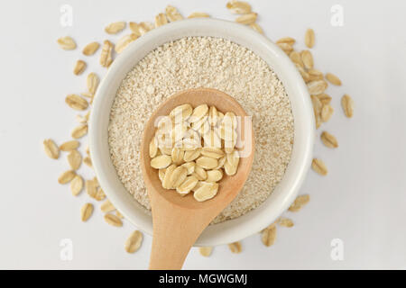 Oatmeal on wooden spoon and oat flour in bowl Stock Photo