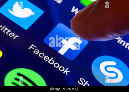 Facebook icon. Finger pressing a shortcut icon to load the Facebook app on a tablet or smartphone screen. Facebook button. Stock Photo