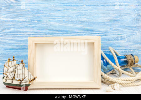 sea vacation background with photo frame, sailboat, rope and bottle against blue wooden boards Stock Photo