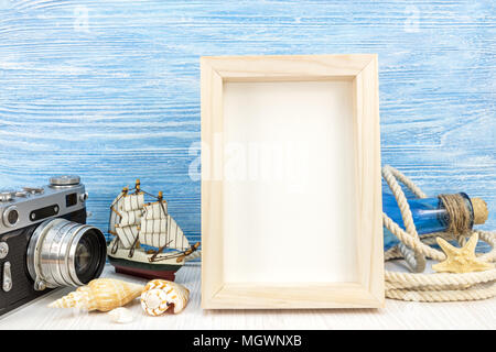 summer holiday background - empty photo frame with classic camera, ship and seashells against blue wooden planks Stock Photo