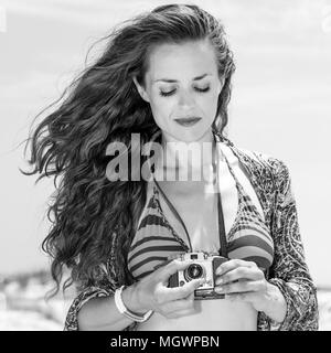 Bohemian vibe vacation. gypsy style young woman in swimsuit on the beach using retro photo camera Stock Photo