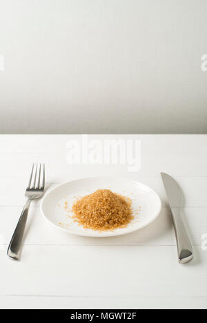 Sugar Junk-food, diet and unhealthy eating concept - close up of sugar on plate with knife and fork. Healthy food concept, presentation of sugar conte Stock Photo