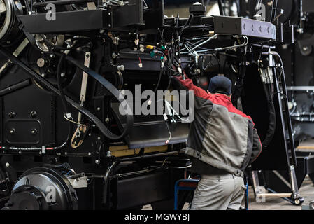 Industrial worker assembles agricultural equipment Stock Photo