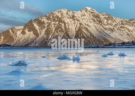 Frozen mountain lake with ice formations on the water surface in Lofoten. Flower-like patterns are pushed up by rocks as the water level lowers in lat Stock Photo