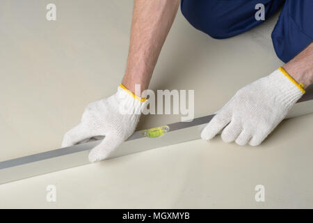 Construction worker measures the quality of floor using spirit level Stock Photo
