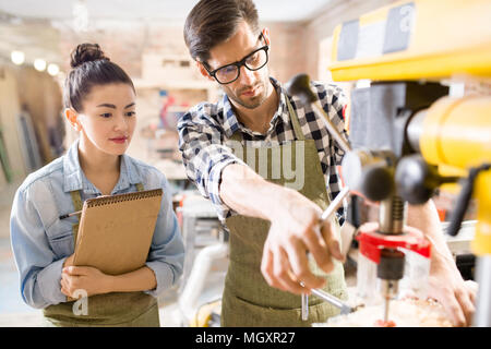 Waist up portrait of  two modern artisans, man and woman, working together using machines in woodworking shop, collaborating on creative project Stock Photo