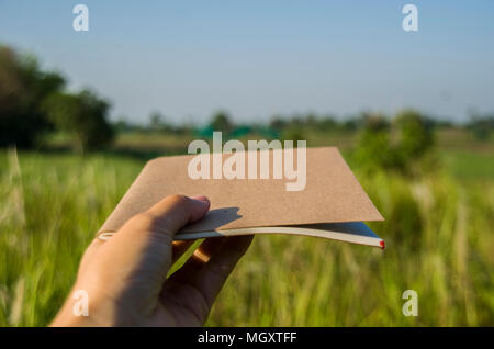 Hand holding the brown notebook with natural light in garden outdoor at Chiang Ma,Thailand. Stock Photo