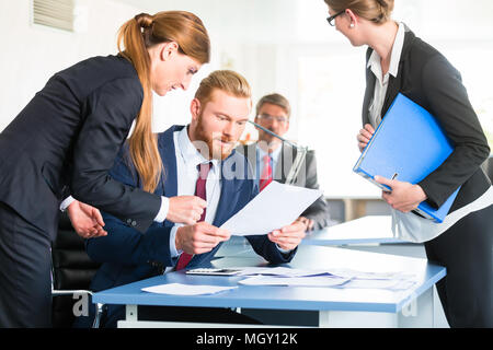 Manager checking documents in front of assistants Stock Photo