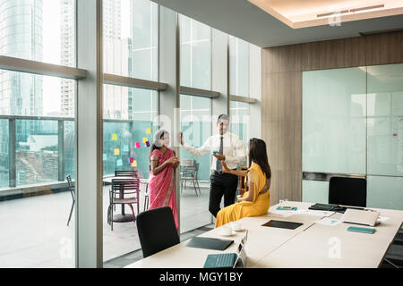 Three Indian employees talking during break in the meeting room Stock Photo