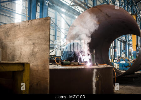 Blue-collar worker welding in the interior of a factory Stock Photo