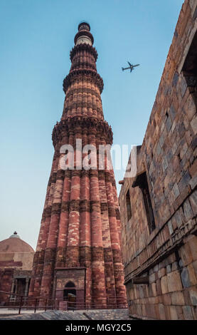 Tiny aeroplane flying across the sky during the blue hour in the Qutub Minar complex, the heritage wonder of New Delhi