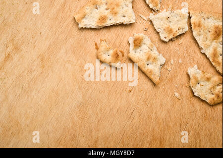 Broken cracker and crumbs on wooden background. Stock Photo