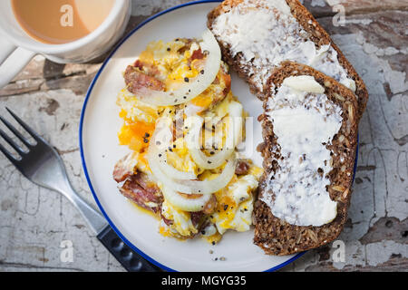 Scrambled eggs with bacon, sausage and onion with wholegrain bread and coffee Stock Photo