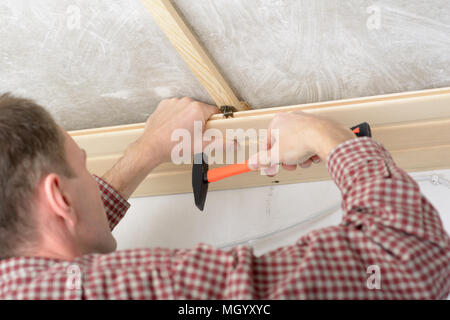 Contractor installing wood panels on a ceiling Stock Photo