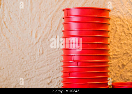 Stack of Colorful Tubs isolated with clipping path.stack of red iron buckets.metal pails.Buckets isolated on the beige background.minimal concept idea. Stock Photo