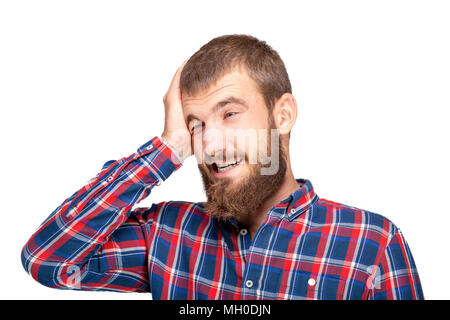 A young bearded man in a plaid shirt is experiencing an annoying mistake or oversight. Emotional portrait on a white background. Stock Photo