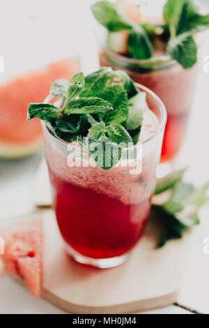 Closeup shot of glass filled with cooling watermelon lemonade and topped with green fresh leaves. Stock Photo