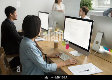 Multiracial colleagues working together on desktop computers in  Stock Photo