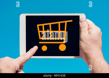 Man holding a tablet device and touching a shopping cart icon. Stock Photo