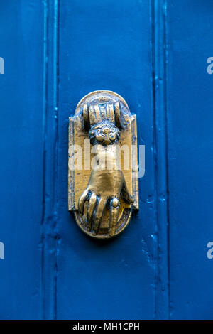 A door knocker in the shape of a hand on a blue door, London, UK Stock Photo