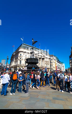 Busy square - Tourists walking in Piccadilly Circus and sitting on the steps of Shaftesbury Memorial Fountain, London, UK Stock Photo