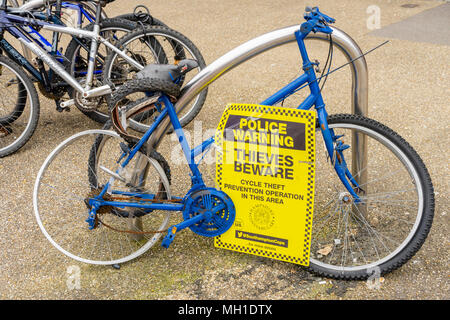 Blue dishevelled bike on display in a street, Hampshire Constabulary police issuing a warning on a sign 'Thieves Beware', England, UK Stock Photo