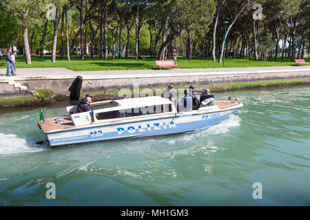 Italian Polizia patrol boat on Rio del Giardini, Castello, Venice, Italy with a team of police officers , couple watching them pass and Sant'Elena beh Stock Photo