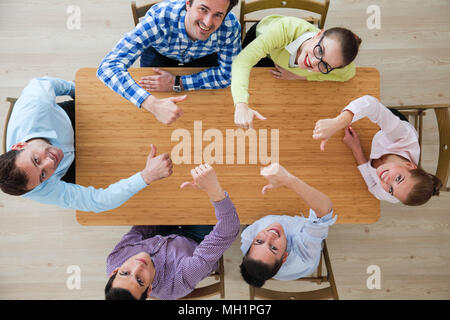 Coworkers with thumbs up sitting at the office table, top view Stock Photo