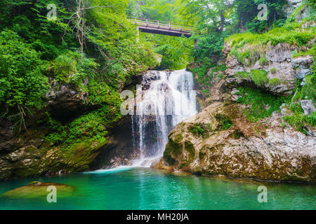 Sum waterfall of Radovna River flowing through Vintgar Gorge, Triglav National Park, Julian Alps, Slovenia. Sum waterfall wooden bridge Vintgar Canyon Stock Photo