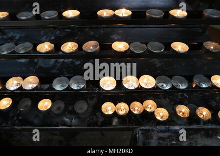 Burning candles in church. Concept of religion. Sacred light, dark background. Bright yellow light in the evening, close-up. Many lighted candles in c Stock Photo