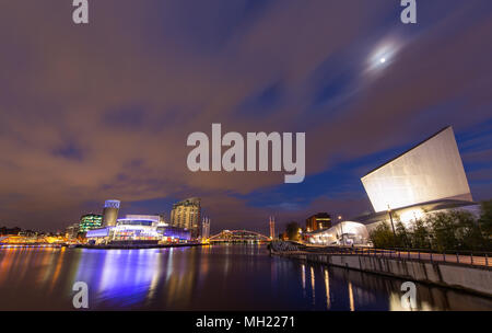 Night view of The Lowry Theatre & galleries, Imperial point building, Millenium lift foot bridge and Imperial war museum at Salford Quays, Trafford, G Stock Photo