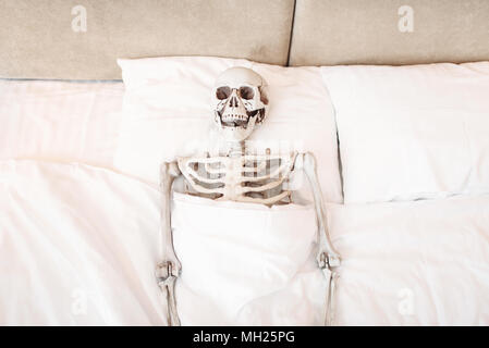 Funny human skeleton is lying in bad Stock Photo