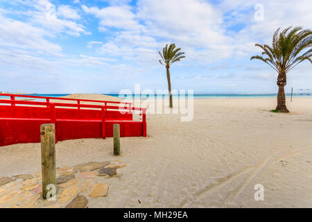Red footbridge and palm trees on sandy Alcudia beach at early morning, Majorca island, Spain