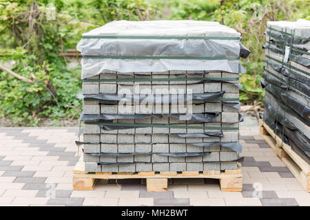 Stack of gray pavement slab on wooden base. Concrete stone paving flag. Isolated on white Stock Photo