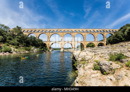Kayaking under the three tiered Roman aqueduct over the river Gardon, known as Pont du Gard on a beautiful summer day in Provence, south of France Stock Photo