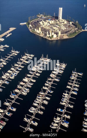 An aerial view shows one of four artificial islands where oil wells are operating just off shore in San Pedro Bay within sight of the city of Long Beach, California, USA. The novelty is that the storage tanks, derricks, pumps and other equipment necessary to extract crude oil from under the sea are camouflaged and soundproofed by tropical landscaping, waterfalls and building facades designed to resemble an island resort as seen from the city's shoreline. Some 1,450 wells have been drilled to depths of 2,000 to 11,000 feet (610 to 3,353 meters) since the four islands were created in 1965. Stock Photo