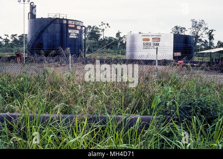 An oil pipeline and wash and surge oil tanks in Ecuador, South America, are evidence of the intrusion by the  petroleum industry in the Oriente jungle region of the Amazon. The discovery of crude oil there in the 1960s by American oil company Texaco has brought environmental and cultural destruction to the pristine rainforest and the lives of its indigenous peoples. Lawsuits have since been brought against Chevron, Texaco's successor, to clean up contamination of the land and rivers caused by oil spills and toxic wastewater that have brought chronic health problems to the native population. Stock Photo