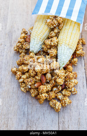 Popcorn caramel mix macadamia and almond taste in paper bag on wood table with copy space. top view. Stock Photo